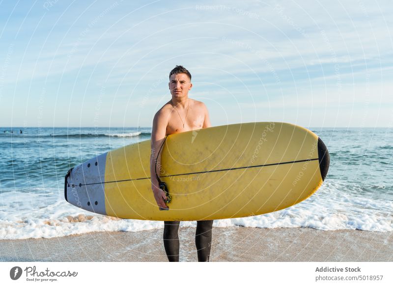 Young man with surfboard walking on beach surfer sea wave active sporty summer ocean shirtless male young shore seashore activity sand vacation athlete seaside