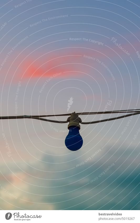 Low angle view of dark blue lamp hanging outdoors from an electric light cord against evening sky. Lamp hanging outdoors lamp against sky technology energy