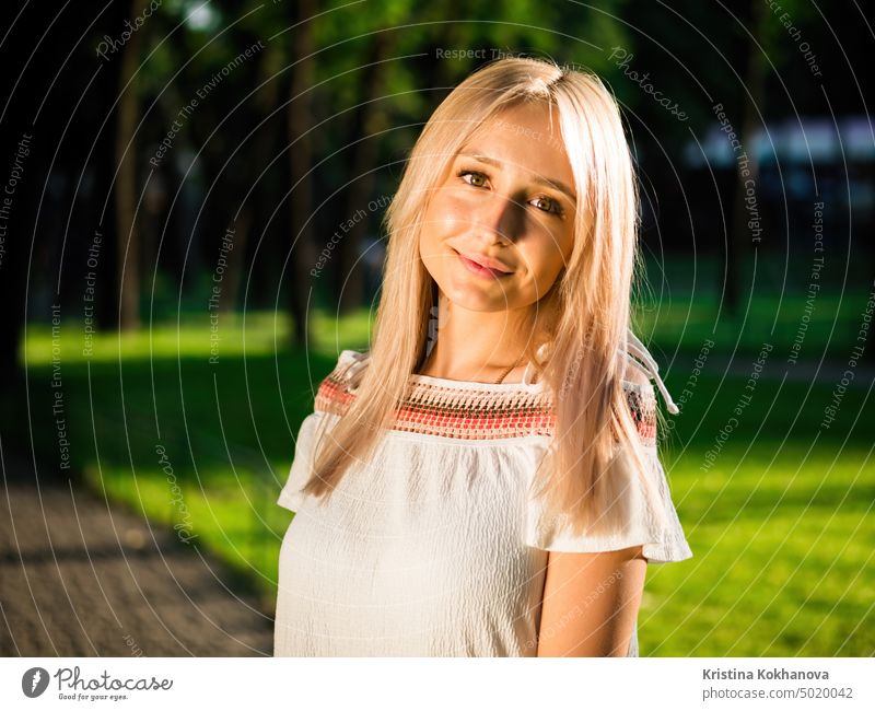 Beautiful blonde woman in white dress posing on green background in park at summer beautiful beauty female hair lifestyle portrait attractive cute fashion happy