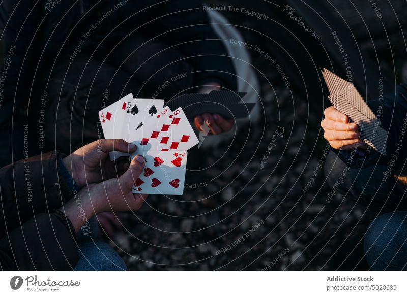 Crop hands of three children playing cards in a train track kids camping sitting hiking siblings discovery young friends group of kids excited activity log