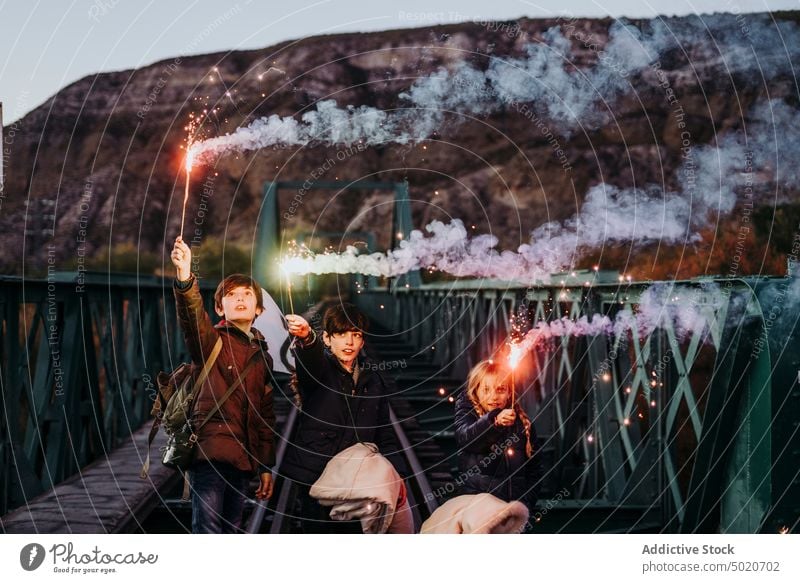 Group of young friends with sparkles on a bridge friendship happy group fun lifestyle celebration adult youth smiling together joyful laughing hipster people