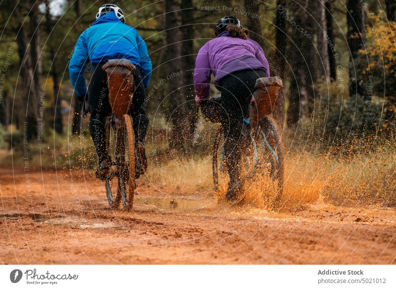 Well-equipped people on road in forest during bike trip adventure bicycle active nature helmet cyclist sport lifestyle speed ride recreation healthy countryside