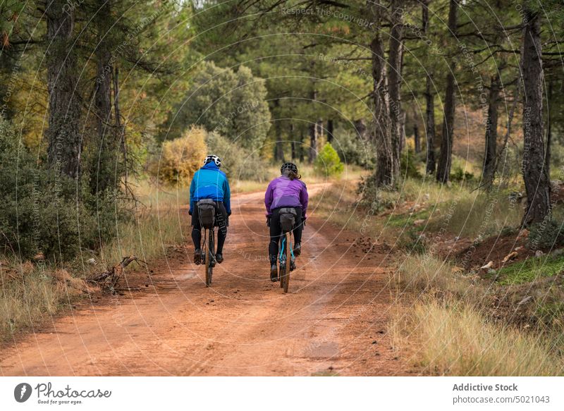 Well-equipped people on road in forest during bike trip adventure bicycle active nature helmet cyclist sport lifestyle speed ride recreation healthy countryside