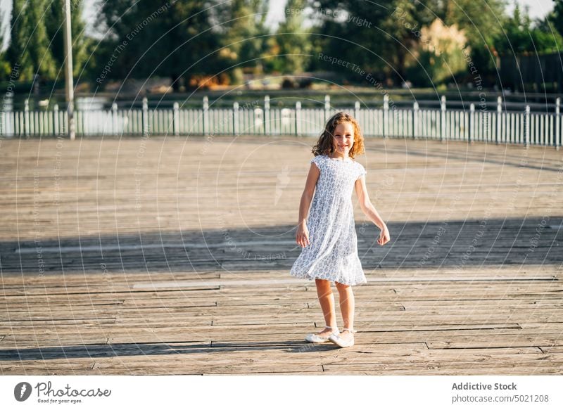 Girl spinning on embankment teen young summer dancing fun boardwalk walkway lifestyle child teenager beautiful person smile pretty cute charming enjoyment