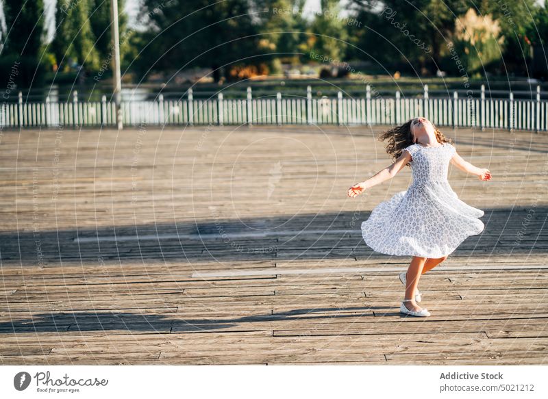 Girl spinning on embankment teen young summer dancing fun boardwalk walkway lifestyle child teenager beautiful person smile pretty cute charming enjoyment