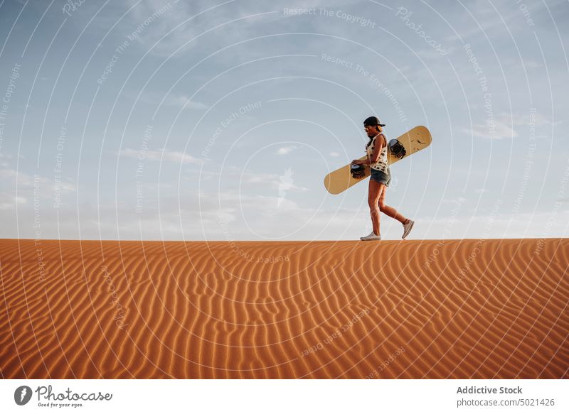 Young woman walking on sand ready for sandboarding sport extreme desert lifestyle leisure fun vacation female travel holiday tourism dry dune enjoyment prepare