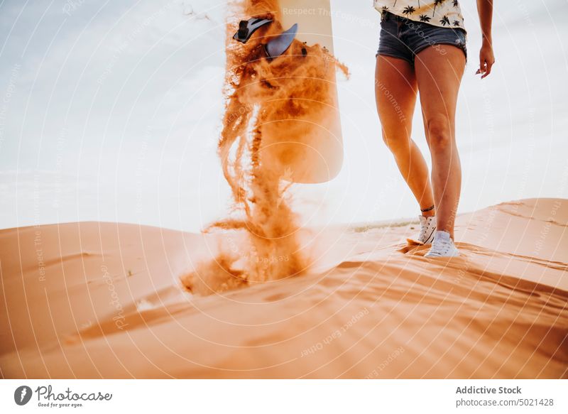 Young woman standing on sand ready for sandboarding covered sport extreme desert lifestyle leisure fun vacation female travel holiday tourism dry dune enjoyment