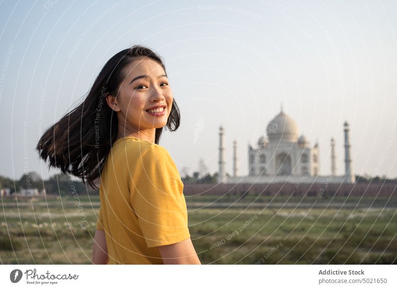 Smiling traveling woman near Taj Mahal taj mahal tourist sightseeing historic landmark mausoleum smile vacation female asian ethnic agra india tourism trip