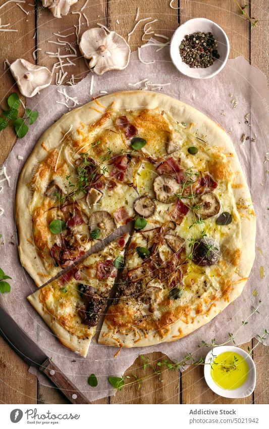 Top view of delicious pizza with basil and tomato sauce placed on wooden table near napkin in kitchen tasty mushroom food yummy fresh lunch cuisine culinary