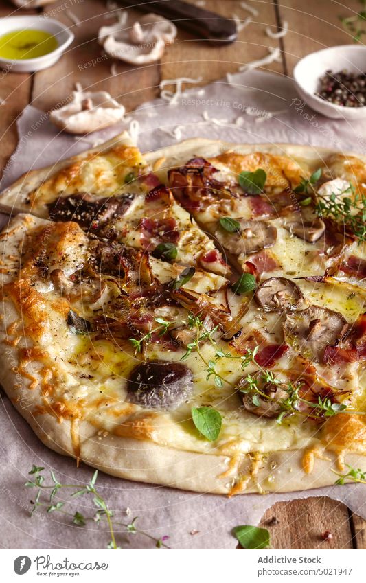 Top view of delicious pizza with basil and tomato sauce placed on wooden table near napkin in kitchen tasty mushroom food yummy fresh lunch cuisine culinary