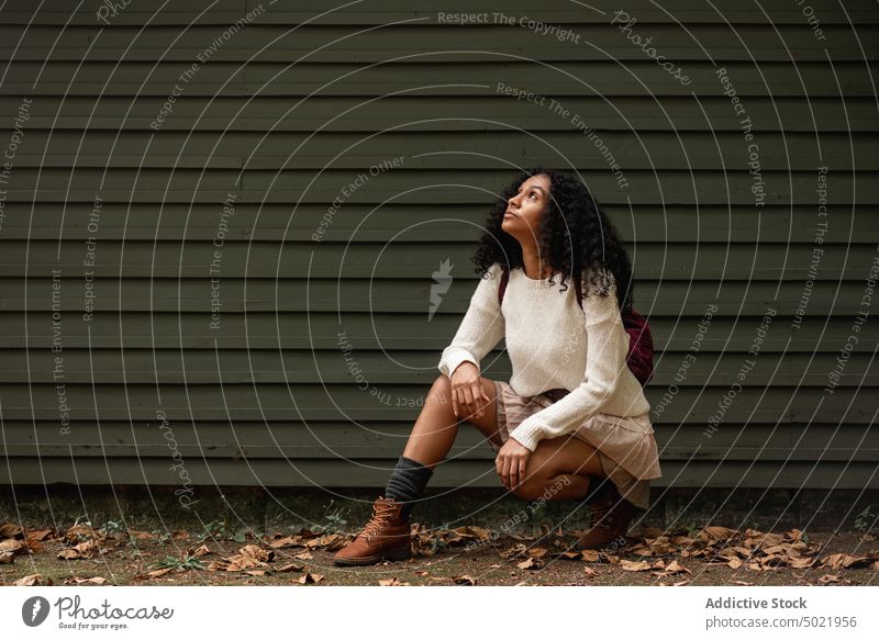 Dreamy black traveler against ribbed wall in village dreamy feminine trip vacation gentle charming woman portrait foliage faded contemplate leaf countryside