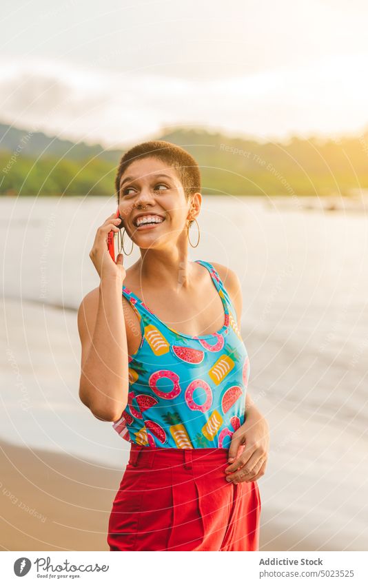 Happy ethnic female talking on smartphone on beach woman summer sea communicate happy young latin american mobile smile short hair cheerful connection