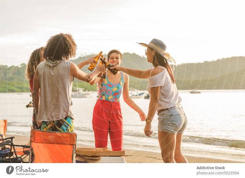 Cheerful friends clinking beer bottles on beach cheerful summer gather hangout together happy group young drink friendship toast party alcohol fun cheers