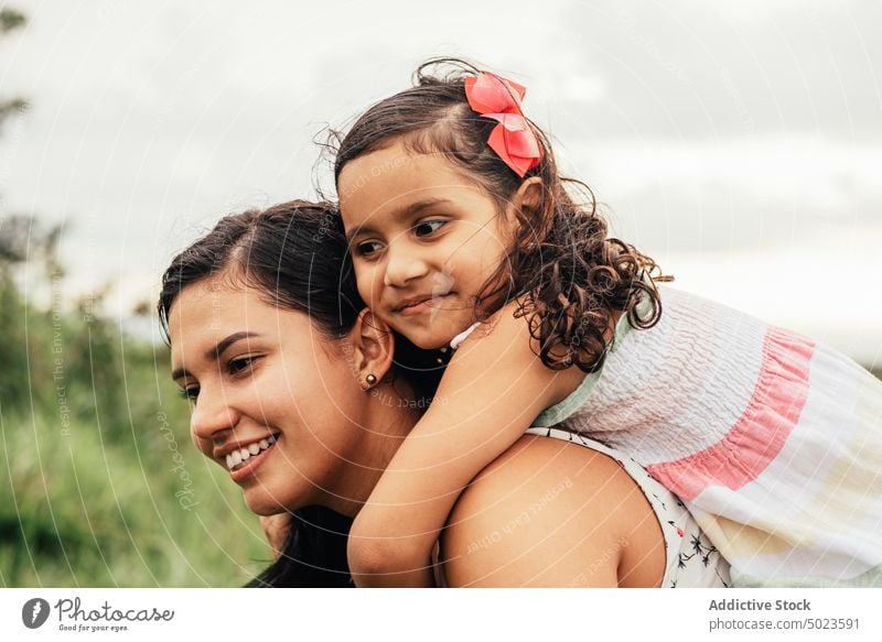 Mother carrying daughter on back in nature mother piggyback weekend ride love smile summer woman girl happy together field cheerful kid child fun joy