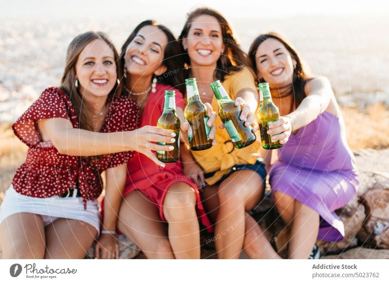 Happy friends clinking bottles of beer women toast joy girlfriend fun cheers group gather female drink alcohol happy beverage together glass celebrate cheerful