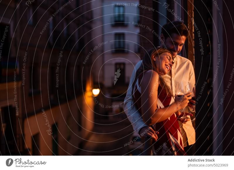 Happy couple of lovers drinking wine on balcony lean on girlfriend boyfriend together twilight enjoy romantic celebrate affection event embrace relationship