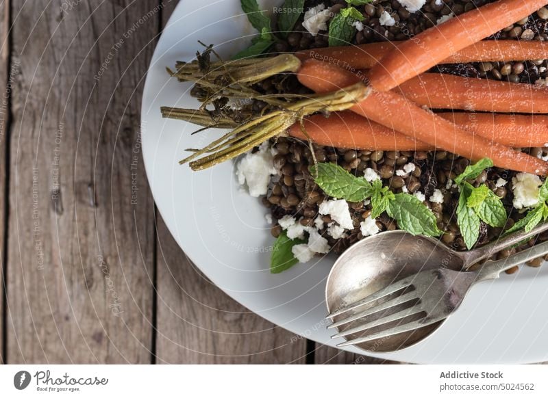 Served salad with lentils and carrot served delicious dressing cheese sauce legume table eating rustic spoon board mint seasoning plate meal green dinner bowl