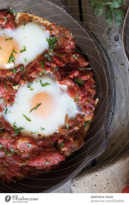 Frying pan with tomatoes and eggs shakshuka served delicious spicy fried sauce red wood breakfast food dish parsley rustic gourmet meal bread morning nutrition