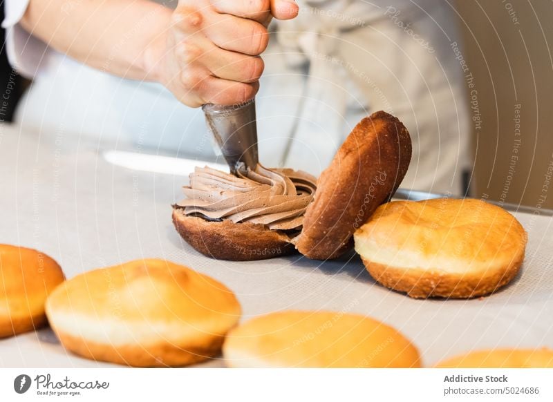 Unrecognizable baker adding cream on cakes in kitchen cook dessert pastry bag vegan sponge bakehouse chocolate delicious culinary tasty food chef patisserie