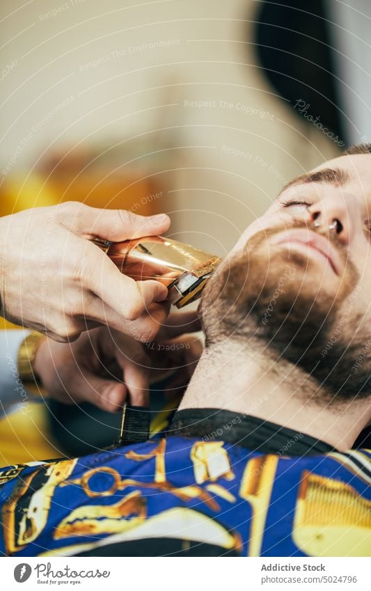 Barber working in a barbershop barber shop beard beauty care client clipper cut elegant hair haircut hairdresser hands head indoor lifestyle male man modern