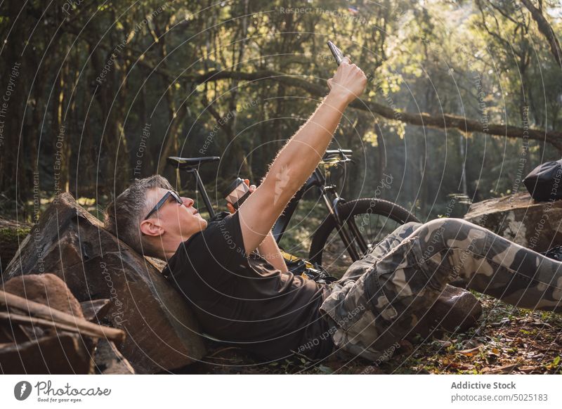 Hiker taking selfie on smartphone in camp hiker moment memory rest stone man using gadget device camouflage ornament pants sunglasses accessory cellphone trip