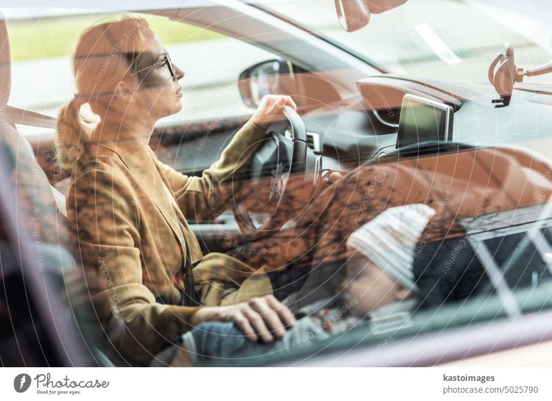 Mother concentrating on driving family car running errands while her baby sleeps in infant car seat by her site. mother drive child safety vehicle travel boy