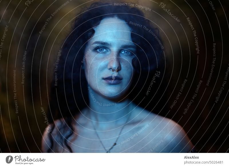 Close portrait of young dark haired woman with curls, light blue eyes and freckles in blue green light Woman Young woman Freckles Curl Brunette long hairs pale