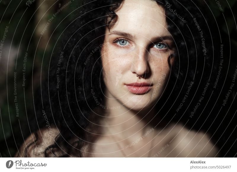 Close portrait of young dark haired woman with curls, light blue eyes and freckles - ivy can be seen in background Woman Young woman Freckles Curl Brunette