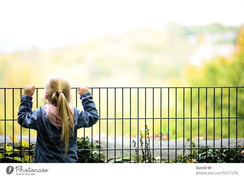 Child in front of a fence looks into the distance Girl explore Observe Far-off places Vantage point Fence cordoned off penned Curiosity Nature inquisitorial