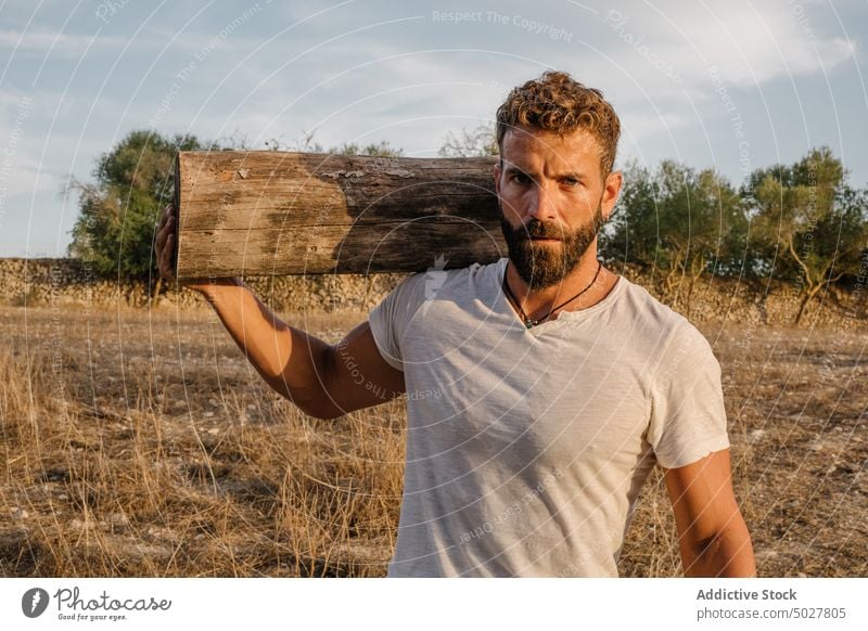 Strong male farmer with log man work countryside carry agriculture strong daytime adult casual worker agronomy beard job t shirt jeans weather nature season