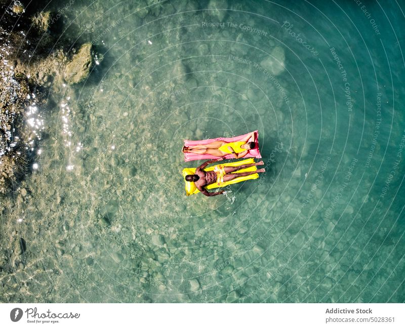 Diverse couple chilling on floats lake summer vacation clean water together weekend travel girlfriend boyfriend holiday diverse multiracial multiethnic black