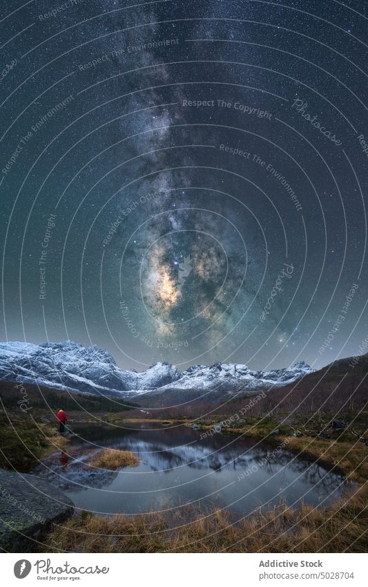 Explorer near lake under starry sky at night traveler milky way mountain winter admire northern explorer lofoten islands norway nature dark highland adventure