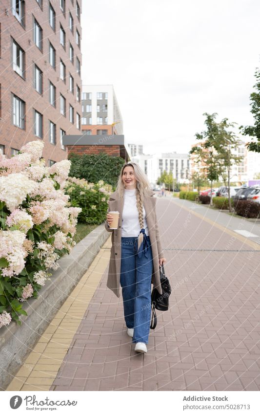 Woman with coffee walking to work woman street morning commute style to go urban pavement female takeaway smile happy cheerful optimist pedestrian street style