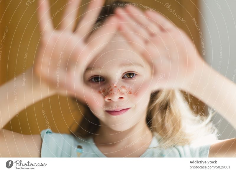 Girl with makeup on face gesturing at camera girl glitter gesture celebrate festive event portrait little adorable kid child fun serious childhood holiday cute