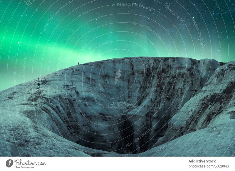 Traveler against night sky with glowing polar lights aurora borealis glacier northern ice formation traveler winter cold frozen iceland vatnajokull green