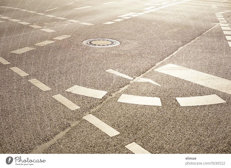 asphalt road intersection with numerous white road markings and a manhole cover Crossroads Lane markings Cycling cycle path Cycle path Arrow turn arrow