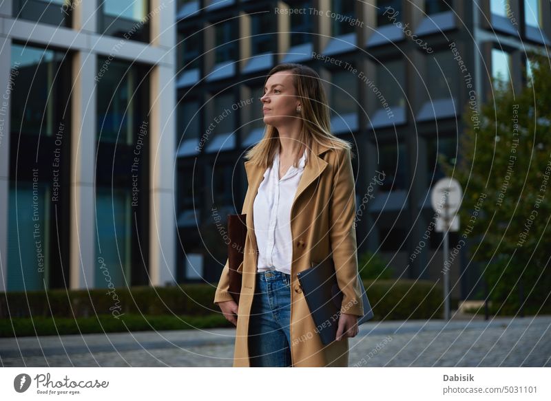 Business woman walking at city street with laptop at summer day. Remote work business freelance computer online outdoors female using person technology