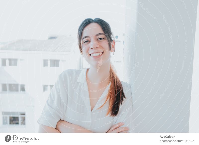 Frontal portrait of a young smiling business student crossing arms while looking straight to camera person businessperson businesswoman confident corporate