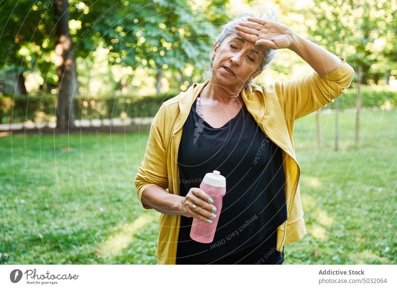 Tired elderly sportswoman wiping sweat wipe break training park tired fitness water touch forehead female senior aged eyes closed exhausted wellness athlete