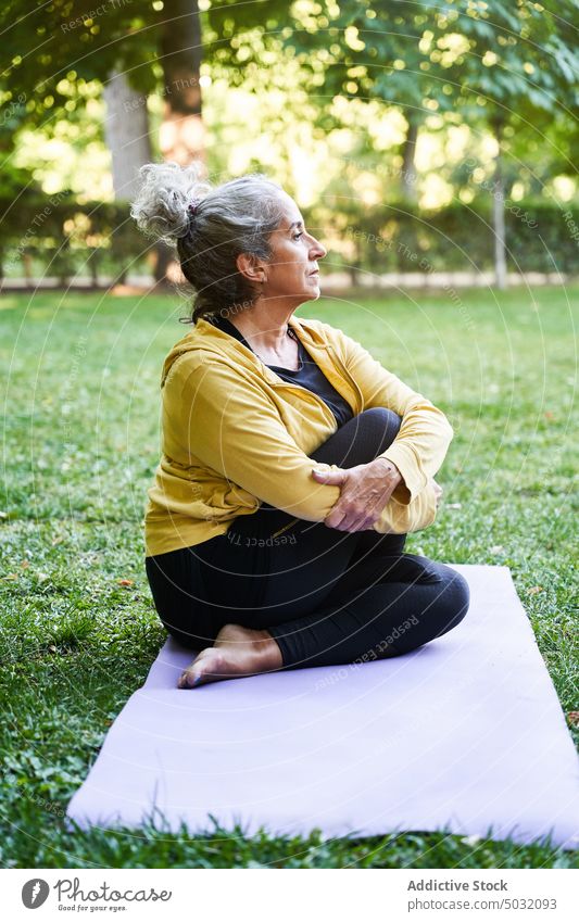 Aged woman stretching during yoga session park twist summer mat asana calm female elderly senior aged practice energy retire barefoot sit stress relief