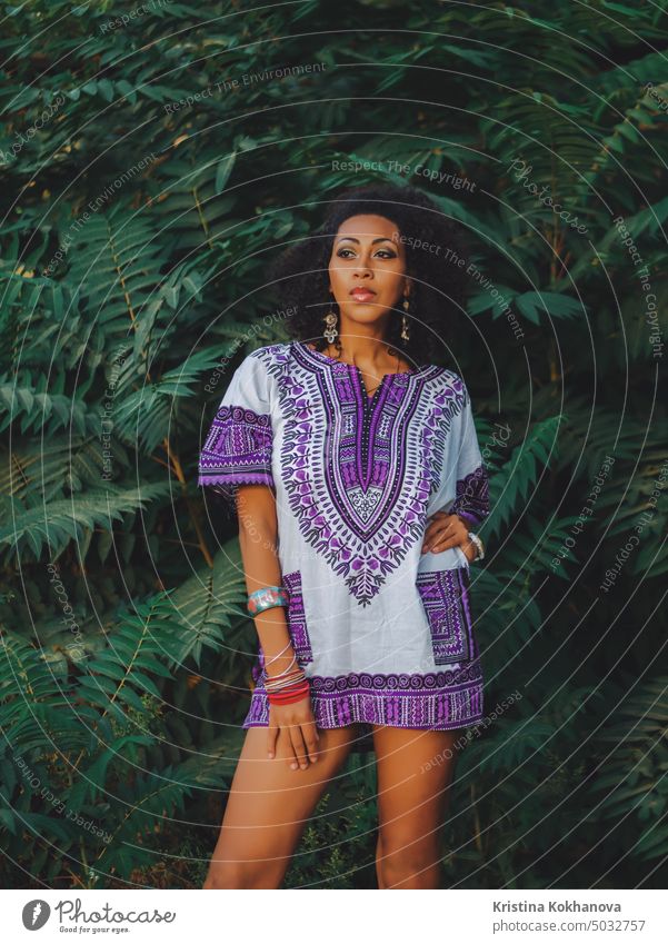 Afro-american woman outdoor. Multi ethnic girl wearing colorful clothing posing, enjoys the nature. Green tropical background african afro beautiful beauty