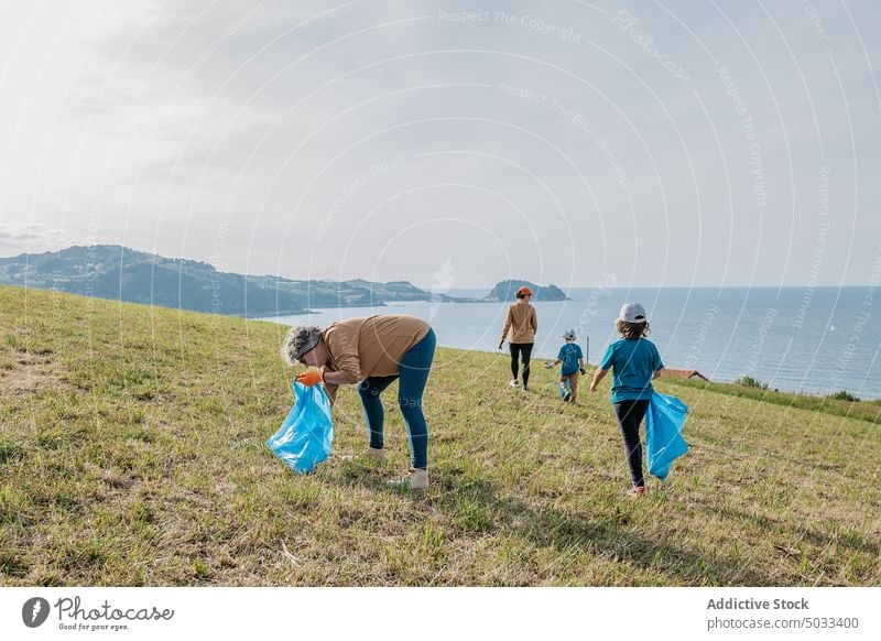 Group of volunteers picking garbage on shore near sea people group trash collect nature eco friendly environment hill recycle ecology rubbish sun green summer