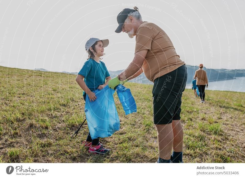 Group of volunteers picking garbage on shore near sea people girl grandfather mother boy group trash collect nature eco friendly environment hill recycle