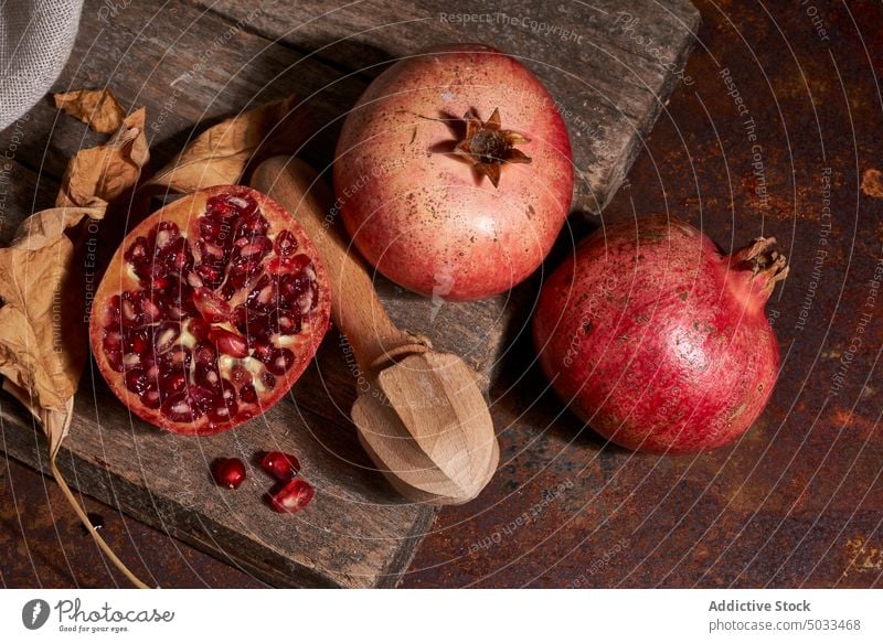 Ripe pomegranate on wooden board ripe fruit dark seed arrangement fresh healthy food gourmet meal natural organic whole color nutrition squeezer chopping board