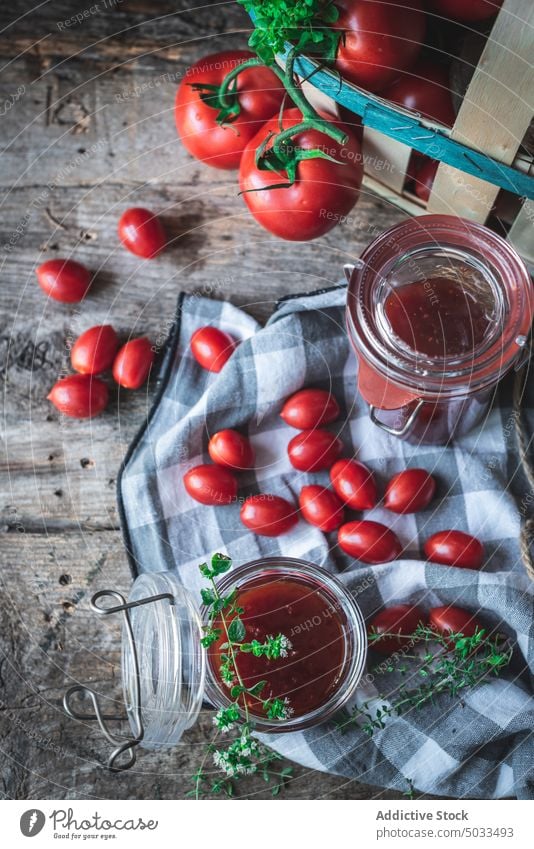 Tomatoes and herbs near jars of jam tomato table basket napkin rustic fresh composition kitchen ripe food organic ingredient vegetable vegetarian vegan natural