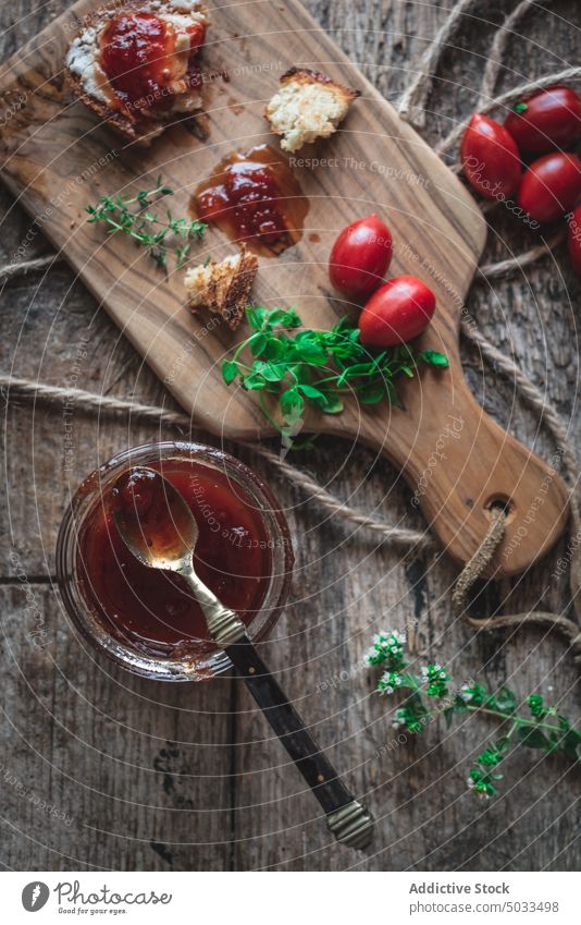 Tomato jam and cutting board on wooden table tomato herb bread spoon kitchen homemade nutrition organic lumber cuisine jar food fresh gourmet timber culinary