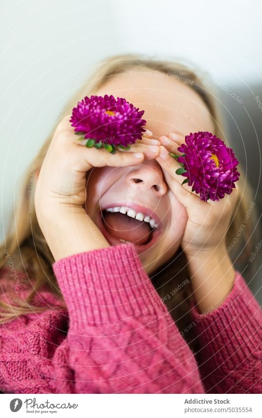 Girl covering eyes with blooming flowers girl portrait smile child cover eyes positive sweater purple blond happy kid cheerful preteen glad joy shy warm