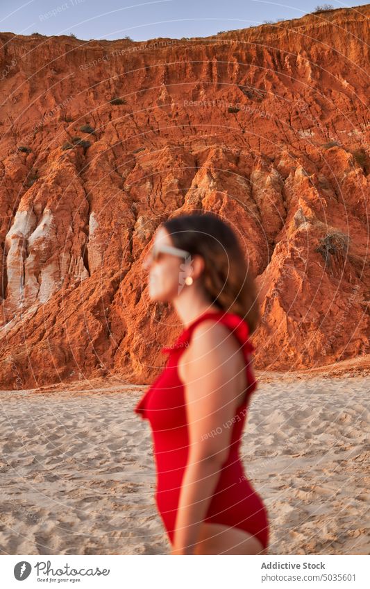 Female traveler on beach at sunset woman cliff sand trip admire weekend resort falesia algarve portugal tourist shore rock dusk twilight sunglasses swimwear