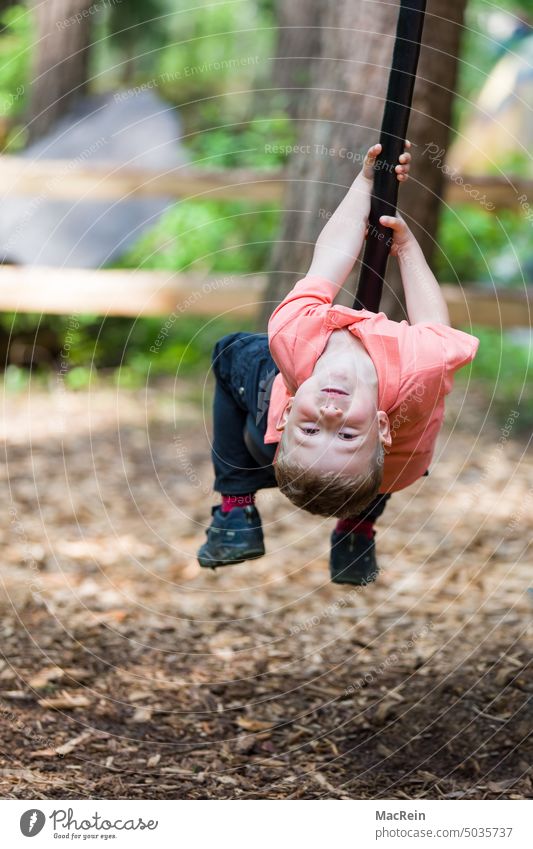 Playing child hanging on a swing, Münchehagen, Lower Saxony 6-8 years old hang out Exterior shot Colour photo Boy (child) Child upside down bent backwards