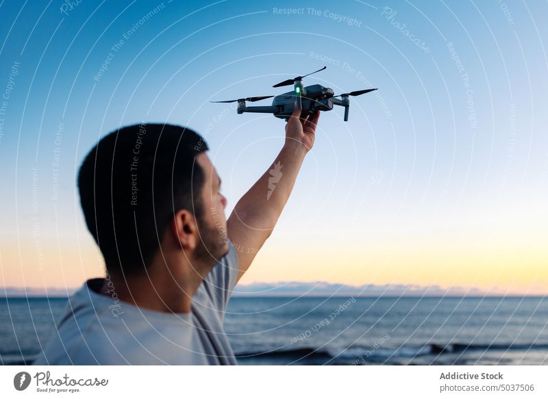 Black man launching drone near sea beach sunset sky wave summer traveler male ethnic black twilight dusk ocean coast evening seaside shore marine lifestyle